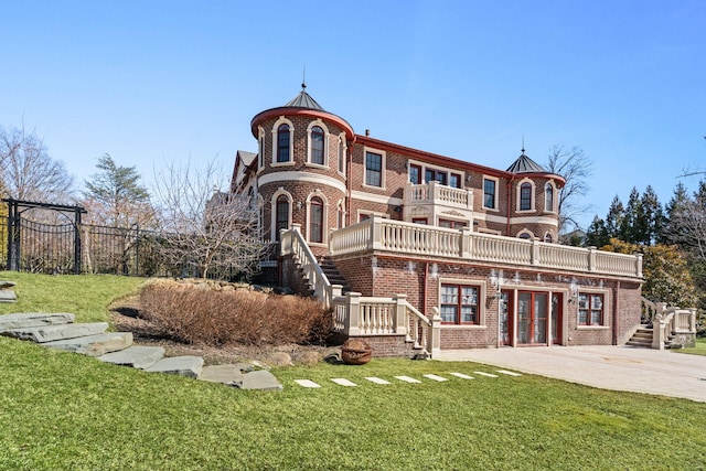 28 Whitney Cir, Glen Cove, NY 11542 - view of front of home featuring stairs, brick siding, a balcony, and a front lawn