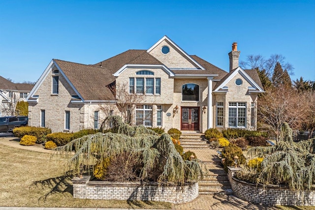 traditional home featuring french doors, brick siding, and a chimney