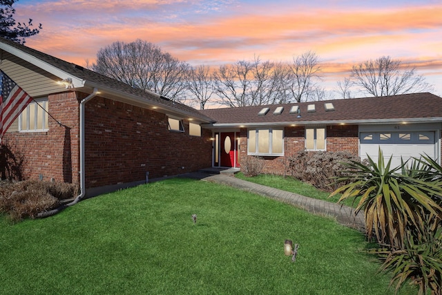 ranch-style home with a garage, a yard, brick siding, and a shingled roof