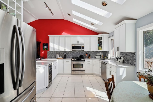 kitchen with white cabinetry, light tile patterned floors, vaulted ceiling with skylight, and appliances with stainless steel finishes