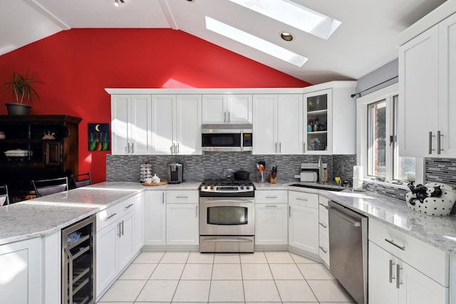 kitchen with light tile patterned floors, appliances with stainless steel finishes, white cabinets, beverage cooler, and a peninsula