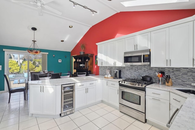 kitchen featuring vaulted ceiling with skylight, wine cooler, stainless steel appliances, a peninsula, and white cabinetry