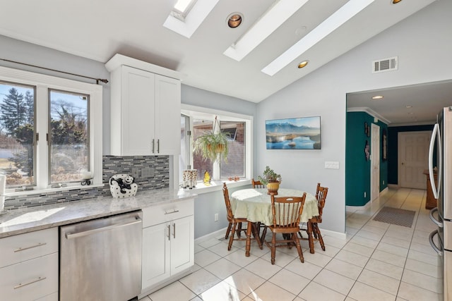 kitchen with a skylight, tasteful backsplash, light tile patterned floors, visible vents, and stainless steel appliances