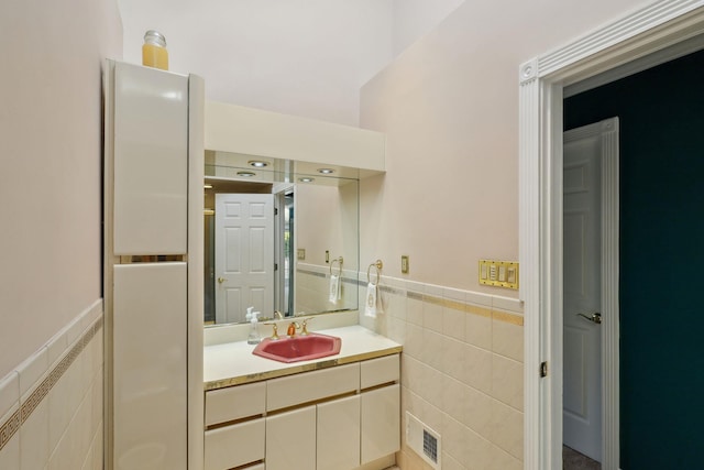 bathroom featuring a wainscoted wall, visible vents, tile walls, and vanity