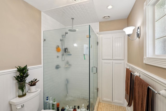 full bath featuring a wainscoted wall, visible vents, a stall shower, and toilet