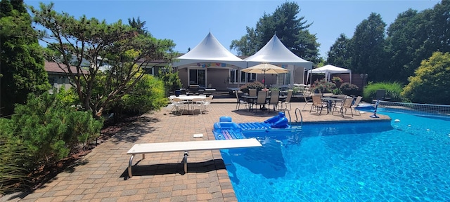 view of swimming pool featuring a patio and a diving board