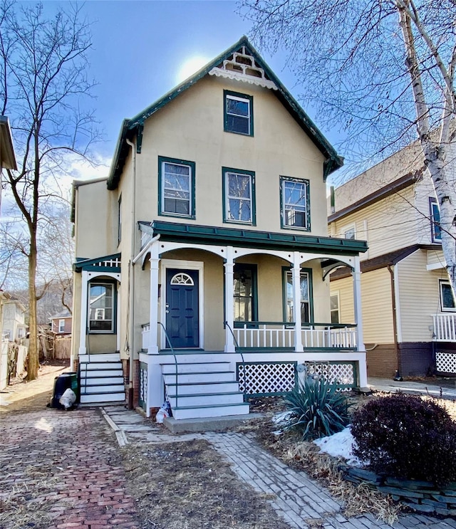 victorian home featuring covered porch and stucco siding