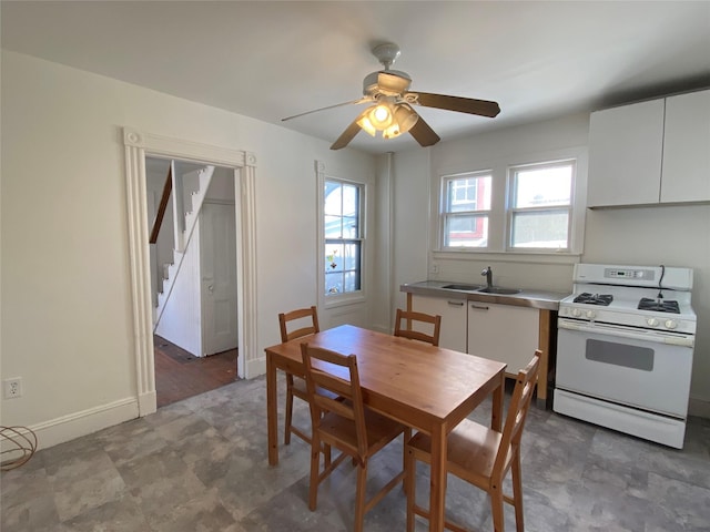 dining space featuring a ceiling fan, stairway, and baseboards