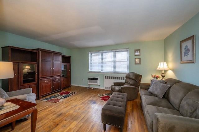 living area with a wall unit AC, light wood-style flooring, and radiator heating unit