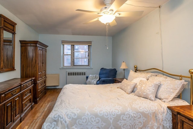 bedroom with radiator, ceiling fan, and wood finished floors