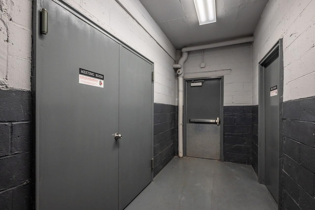 hallway featuring concrete flooring and concrete block wall