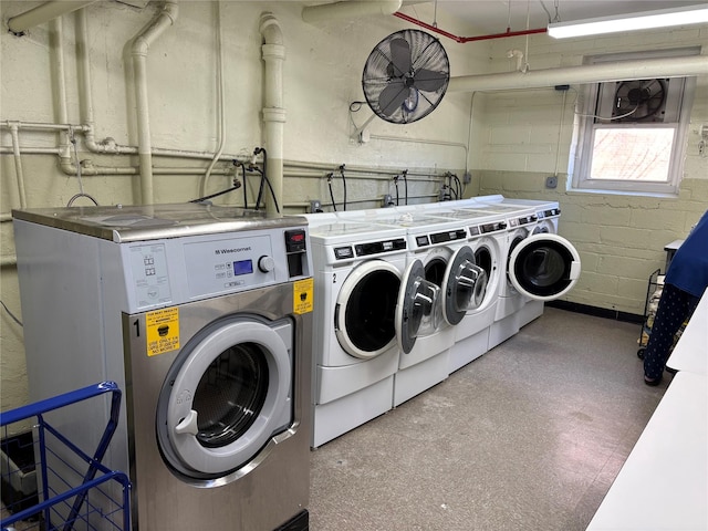 clothes washing area with independent washer and dryer, concrete block wall, and tile patterned floors