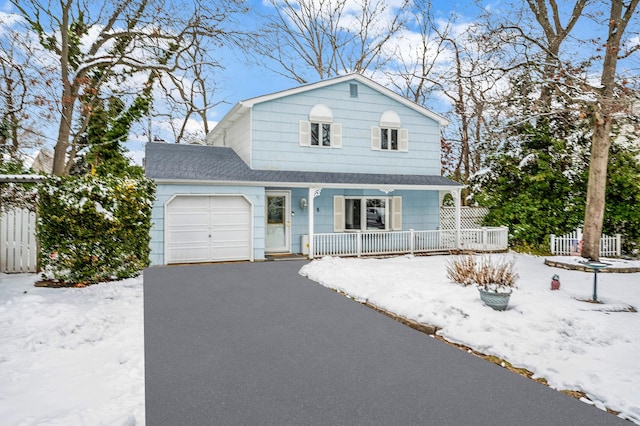 view of front facade featuring a garage, covered porch, driveway, and fence