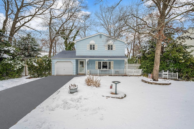 view of front facade with covered porch, driveway, an attached garage, and fence