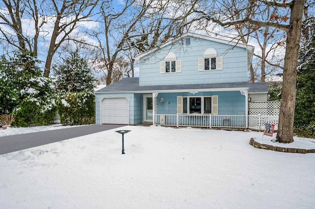 traditional-style home with covered porch, aphalt driveway, and a garage