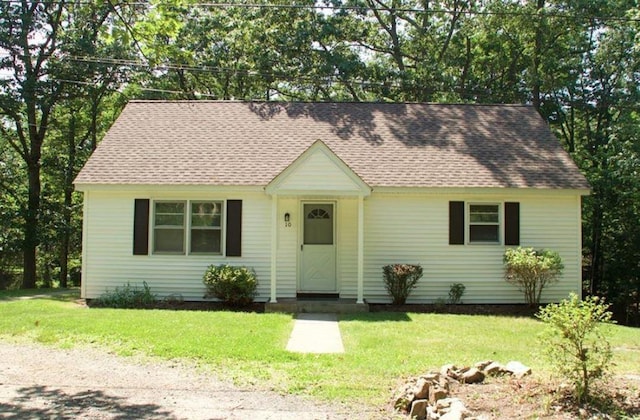 view of front facade featuring a shingled roof and a front yard