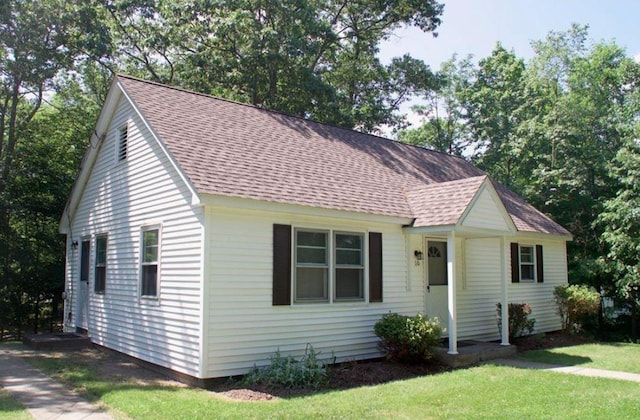 view of front facade featuring a shingled roof and a front yard