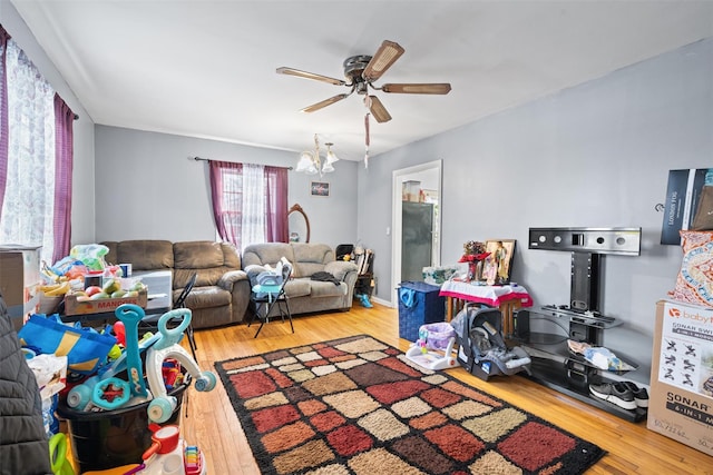 playroom with ceiling fan with notable chandelier and wood finished floors