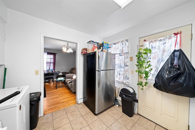 kitchen featuring light tile patterned floors, a baseboard radiator, light countertops, an inviting chandelier, and freestanding refrigerator