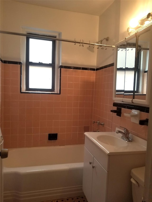 bathroom featuring a wainscoted wall, tile walls, toilet, tub / shower combination, and vanity