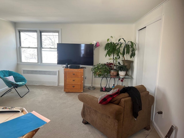 living area featuring baseboards, ornamental molding, carpet flooring, and radiator