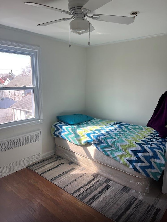 bedroom featuring radiator heating unit, a ceiling fan, and hardwood / wood-style floors