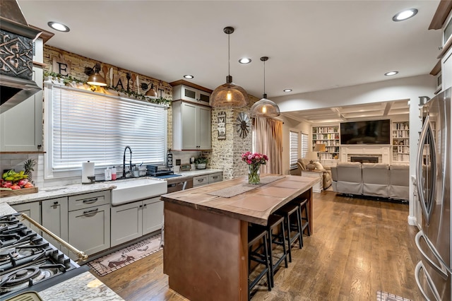 kitchen with dark wood-style floors, a fireplace, freestanding refrigerator, open floor plan, and a sink