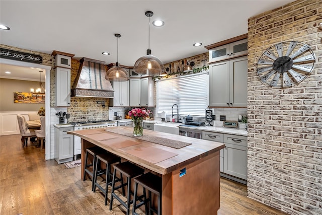 kitchen featuring a kitchen bar, custom range hood, wood counters, and wood finished floors