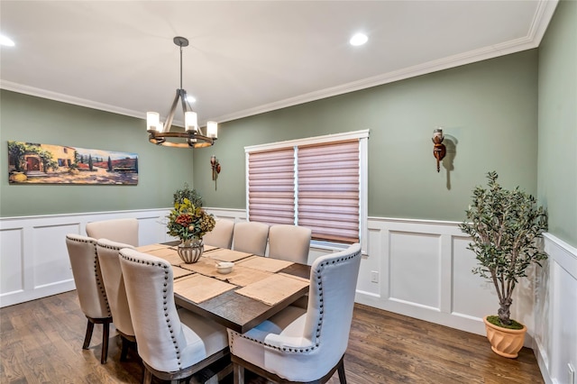 dining area with dark wood-style flooring, a wainscoted wall, crown molding, and a notable chandelier