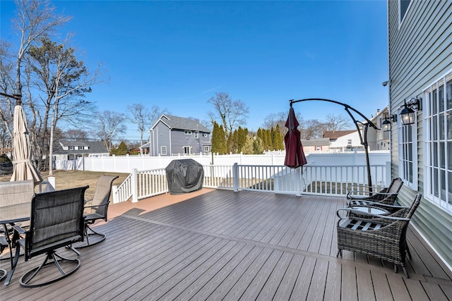 wooden deck featuring outdoor dining area, a grill, a residential view, and a fenced backyard