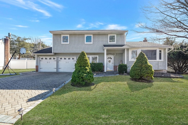 view of front of house with a garage, a front yard, decorative driveway, and fence