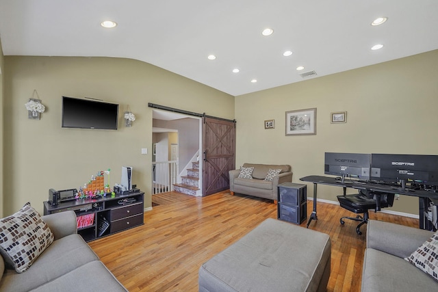 living area with a barn door, visible vents, lofted ceiling, light wood-type flooring, and recessed lighting