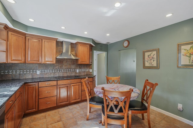 kitchen with baseboards, decorative backsplash, wall chimney exhaust hood, brown cabinets, and black electric stovetop