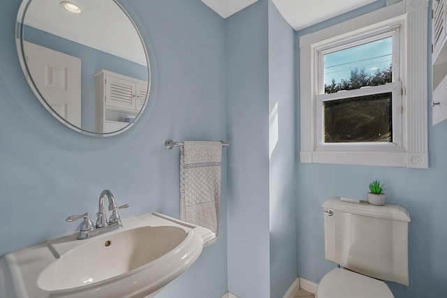 bathroom featuring toilet, baseboards, and a sink