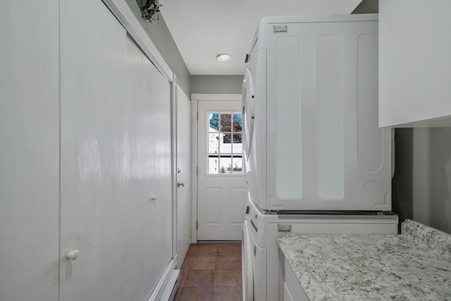 entryway featuring stacked washer and dryer and dark tile patterned floors