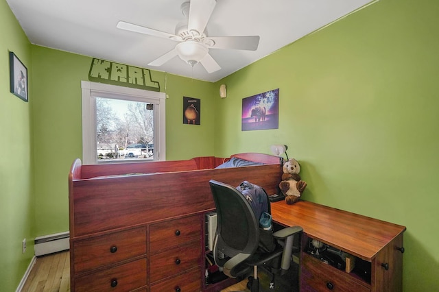 office with baseboards, baseboard heating, a ceiling fan, and wood finished floors