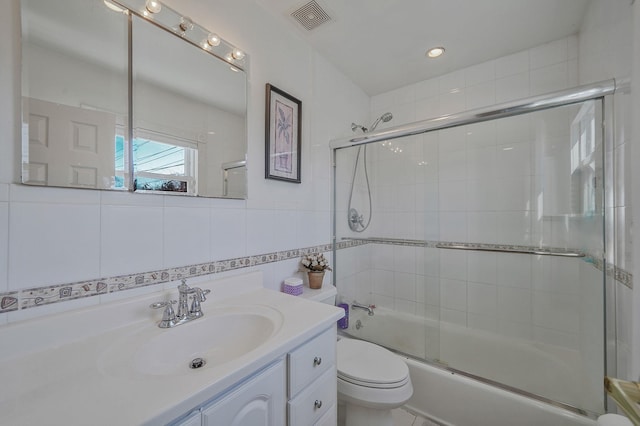 full bath featuring visible vents, toilet, enclosed tub / shower combo, vanity, and tile walls