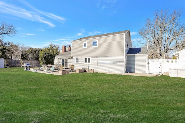 rear view of property featuring a gate, a fenced backyard, a patio, and a lawn