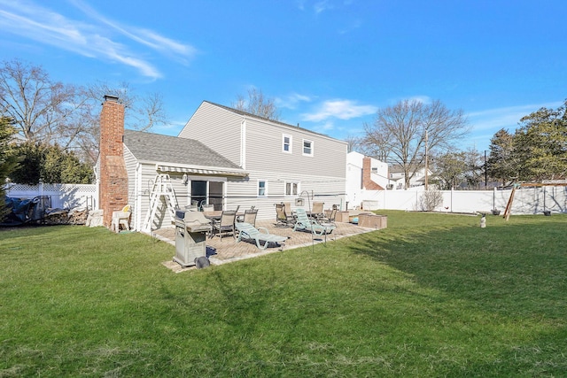 back of house featuring a lawn, a chimney, and a fenced backyard