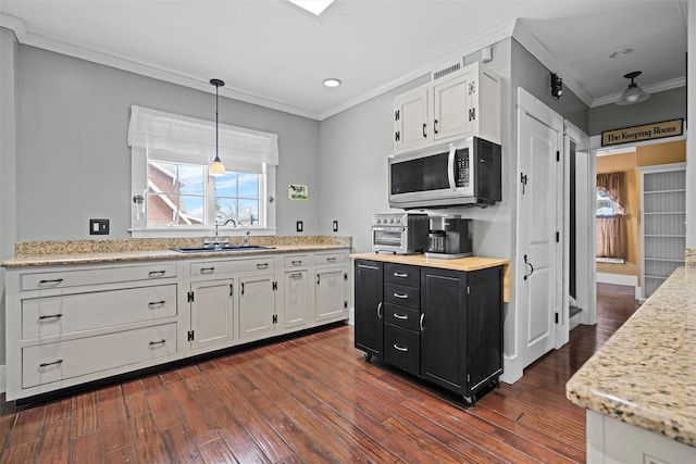 kitchen featuring stainless steel microwave, a sink, white cabinets, and dark cabinets