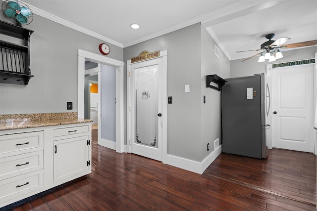 kitchen featuring ornamental molding, dark wood-type flooring, freestanding refrigerator, and white cabinets