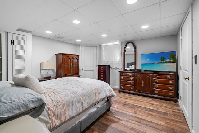 bedroom with a paneled ceiling, wood finished floors, and recessed lighting