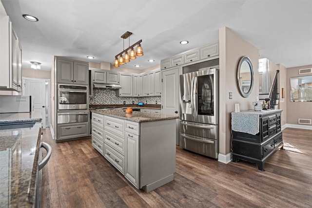 kitchen featuring appliances with stainless steel finishes, dark wood-type flooring, a warming drawer, and decorative backsplash