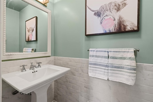 bathroom with a sink, a wainscoted wall, and tile walls