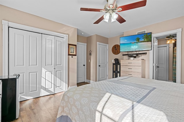 bedroom with light wood-type flooring, ceiling fan, visible vents, and baseboards