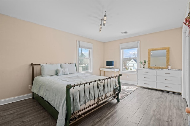 bedroom featuring visible vents, baseboards, and wood finished floors