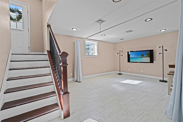 interior space with baseboards, stairs, visible vents, and wood finished floors