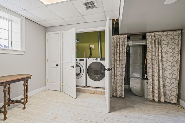 laundry area with laundry area, light wood finished floors, washer and clothes dryer, and visible vents