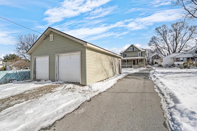 snow covered garage with a garage and fence