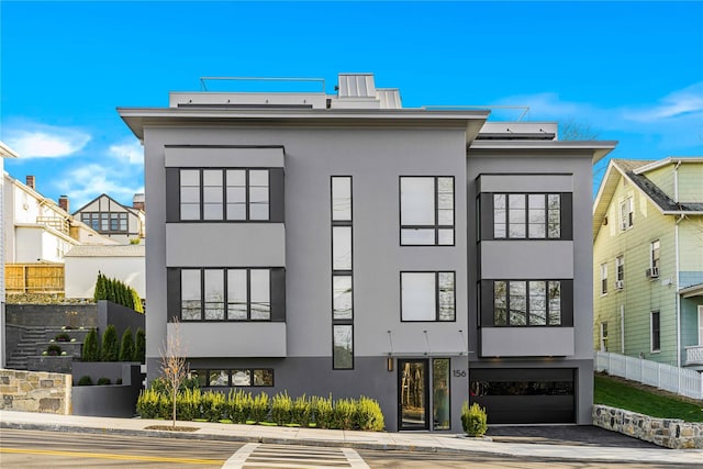 exterior space featuring driveway, a garage, fence, and stucco siding